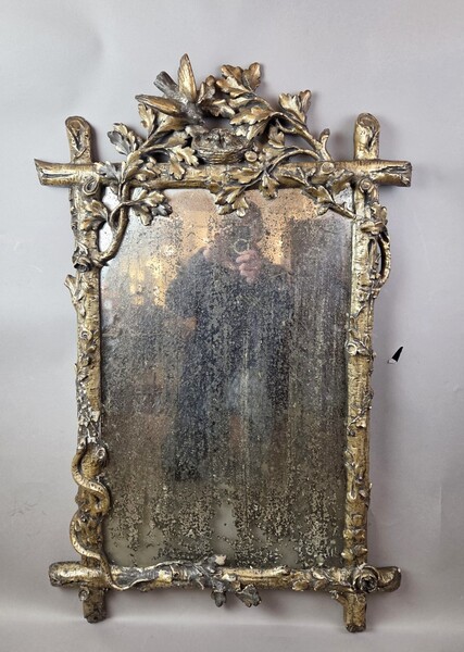 A finely carved giltwood mirror depicting a bird's nest, foliage, and a serpent, 19th century