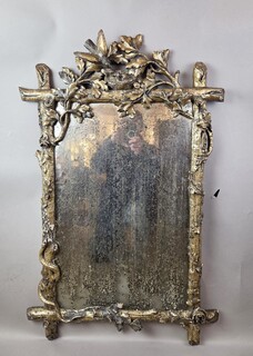 A finely carved giltwood mirror depicting a bird's nest, foliage, and a serpent, 19th century