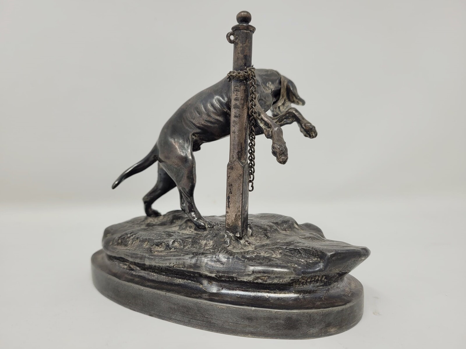 Silver metal sculpture representing a tethered dog