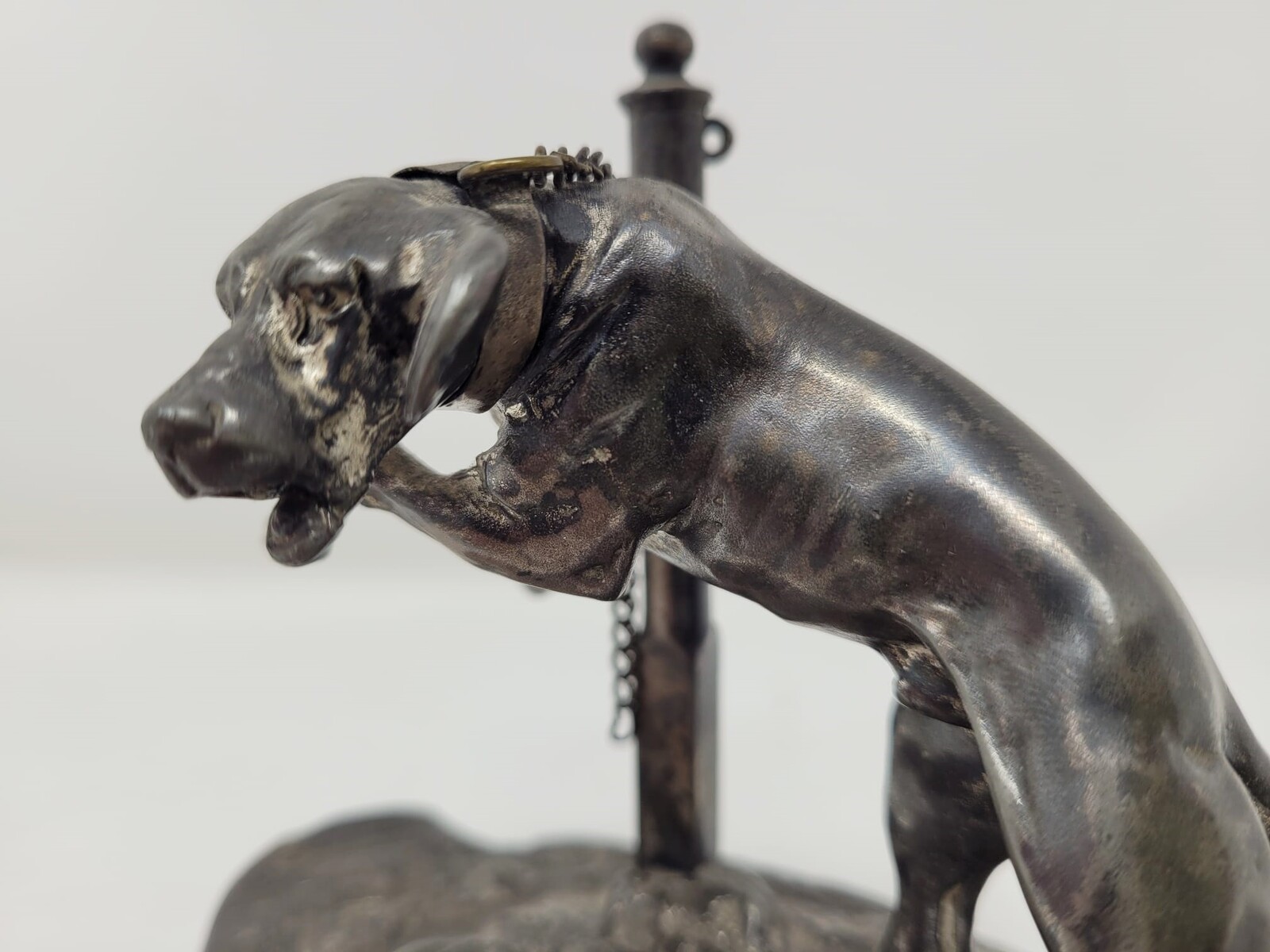 Silver metal sculpture representing a tethered dog